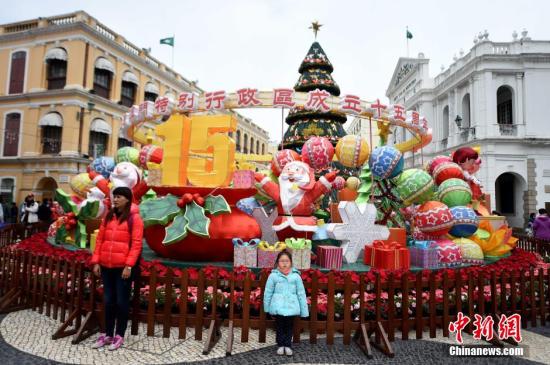 12月18日，遊人在澳門議事廳廣場“澳門特區成立十五周年”花壇前留影。