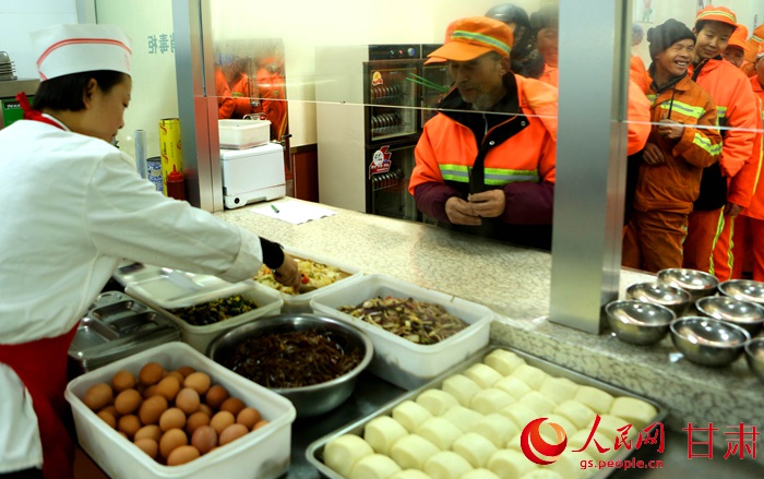 1月13日,在蘭州市城關區亞太慈善定西路免費早餐店,工作人員為環衛工人供應早餐。牟健 攝