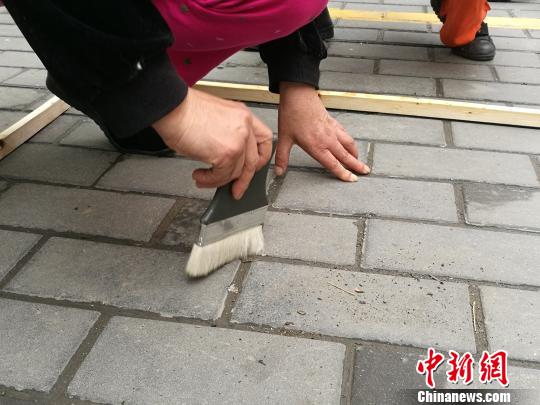 圖為檢查人員用毛刷收集縫隙中的塵土。 張梟 攝