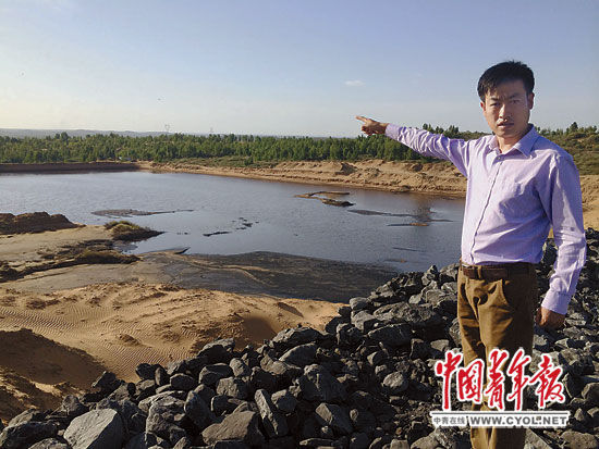 村民張勝利指著煤礦排放污水形成的污水湖說，這片污水湖裝不下污水後，煤礦用水泵把污水抽出排向他家林地的方向，淹了他們村6戶村民家的林地，這片污水湖以前也是林地。本報記者李玉波攝