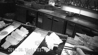 一名食客從取餐臺的托盤上夾取生魚片 攝/法制晚報暗訪組 一名食客從取餐臺的托盤上夾取生魚片 攝/法制晚報暗訪組