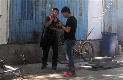 6月20日，平安里育德胡同，男子（左）正給家里打電話讓匯錢，“醫托”守在其旁邊。