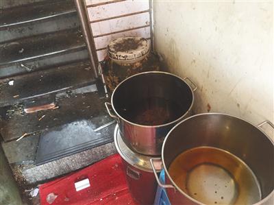 “有飯炸雞”店鋪旁狹窄過道內，潲水桶、盛著油渣的圓桶、面粉等堆在一起，地上散落著煙頭、衛生紙、磚塊。新京報記者 張越攝