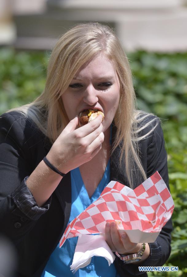 People eat hot dogs during the annual Capitol Hot Dog Day at the Rayburn Courtyard on Capitol Hill in Washington D.C., the United States, on July 23, 2014.